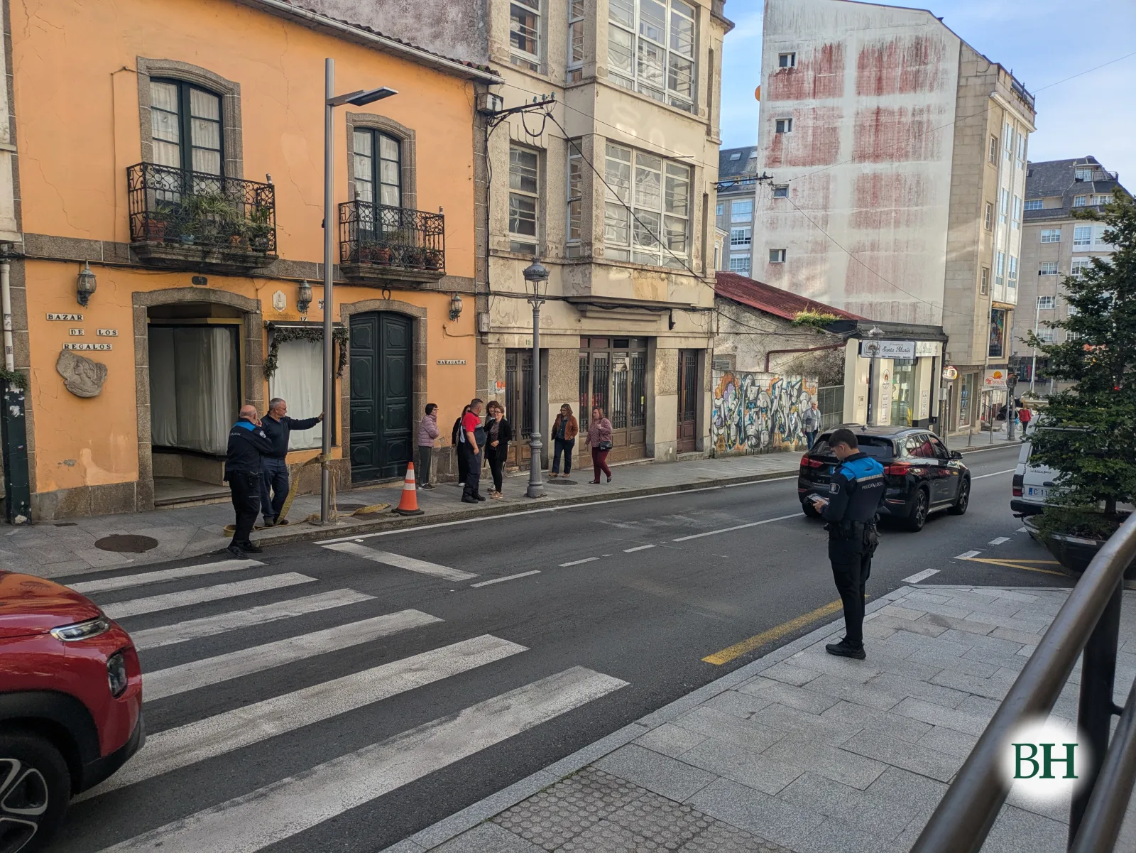 Axentes da Policía Local no paso de peóns da avenida de Jesús García Naveira, coa farola danada á beira da beirarrúa, e veciños mirando desde a outra acera.